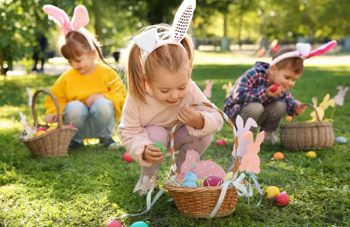Children hunting for colorful Easter eggs in grass garden during Easter egg hunt activity